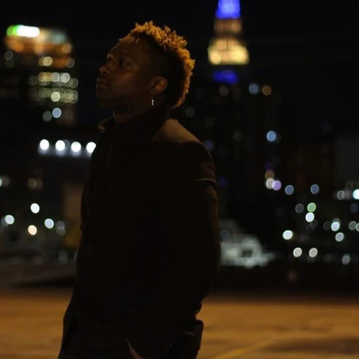 Matthew in a dark suit against Cleveland’s nighttime skyline